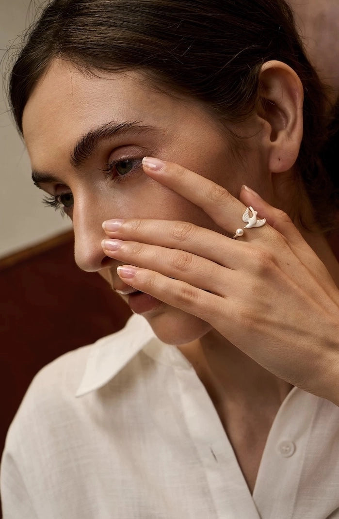 Verstellbarer Ring aus 925er Sterlingsilber mit einem detailreichen Vogel-Motiv in Bewegung und einer kleinen weißen Perle.