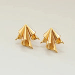 Goldene Ohrstecker in Form von kleinen Origami Papierfliegern mit feinen Linienstrukturen und glänzendem Finish 