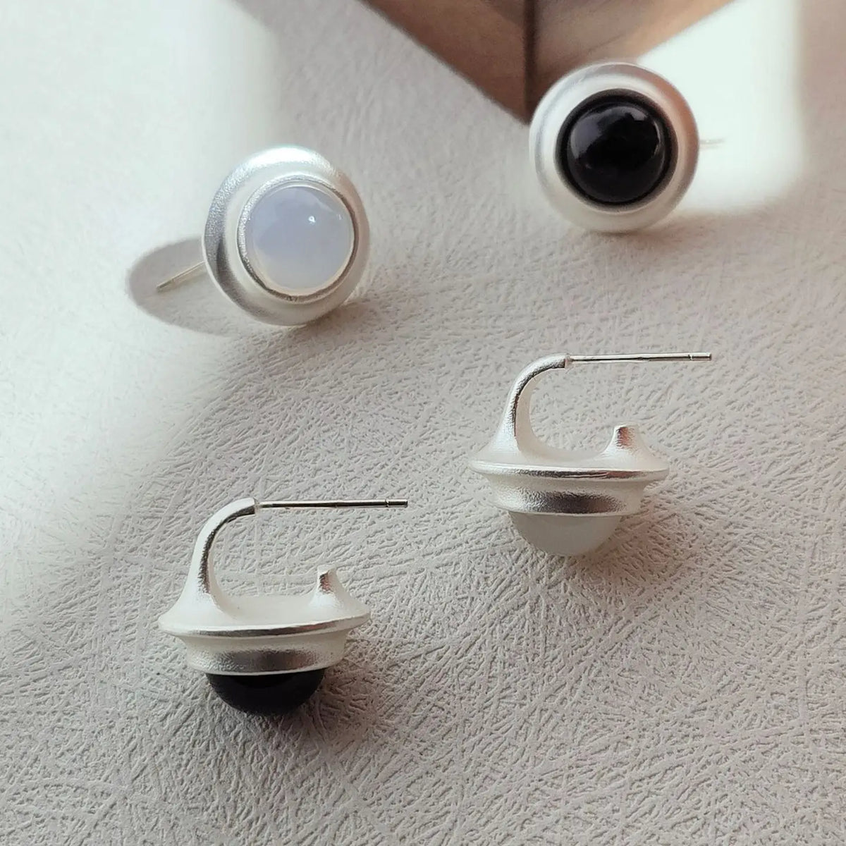 Matte silberne Damen-Ohrstecker mit quadratischem schwarzem und weißem Onyxstein, minimalistisches Design.