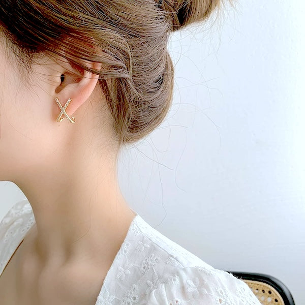 Kleine minimalistische Damen-Kreuzohrringe in Gold mit funkelndem Steinbesatz, Nahaufnahme.