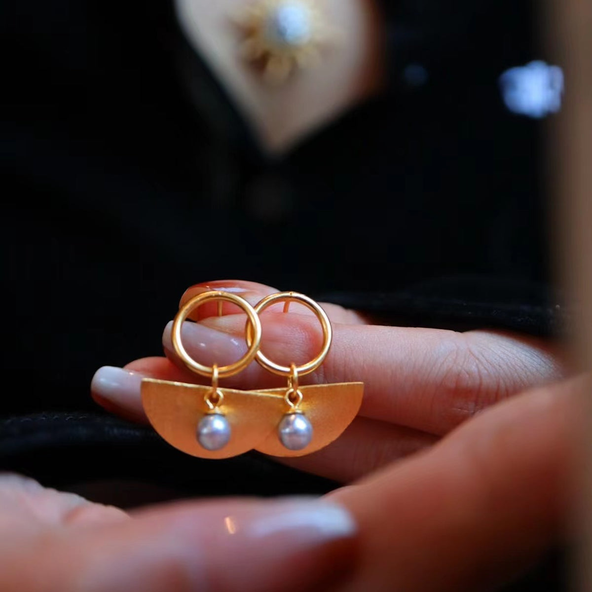 Gold-Vermeil Ohrringe in Halbmond-Form mit einer grauen Akoya-Perle und hängenden Goldelementen.