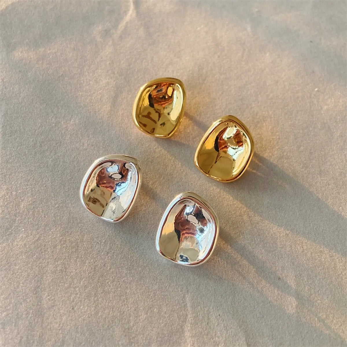 Große, organisch geformte Button-Ohrstecker für Damen mit verspiegelter Oberfläche in Gold und Silber.